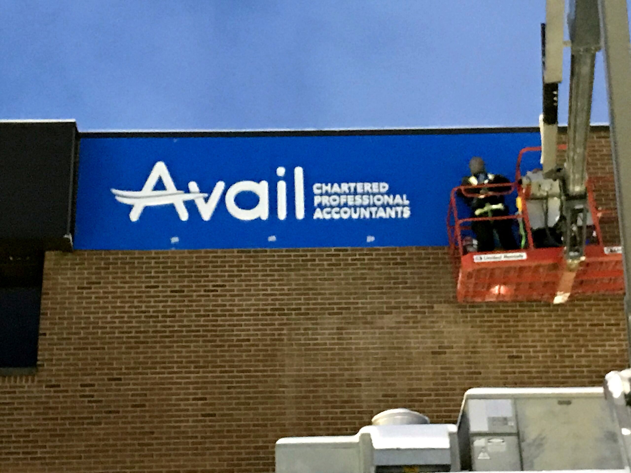 SK Signs installer on a boom lift mounting the Avail sign