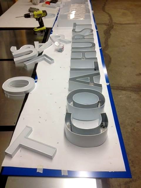 Cut dimensional letters spelling Coalhurst laid out on a shop table