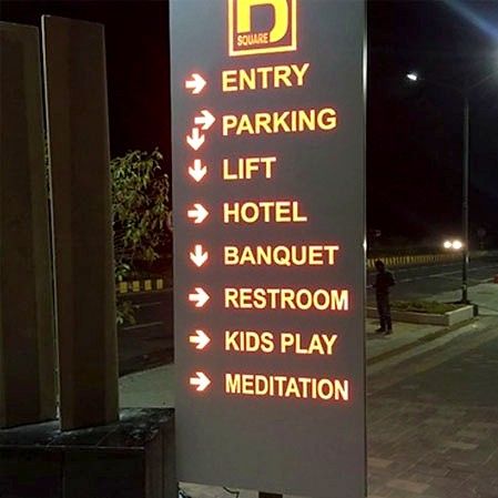Illuminated directional sign listing entry, parking, lift, hotel, banquet and restroom at night